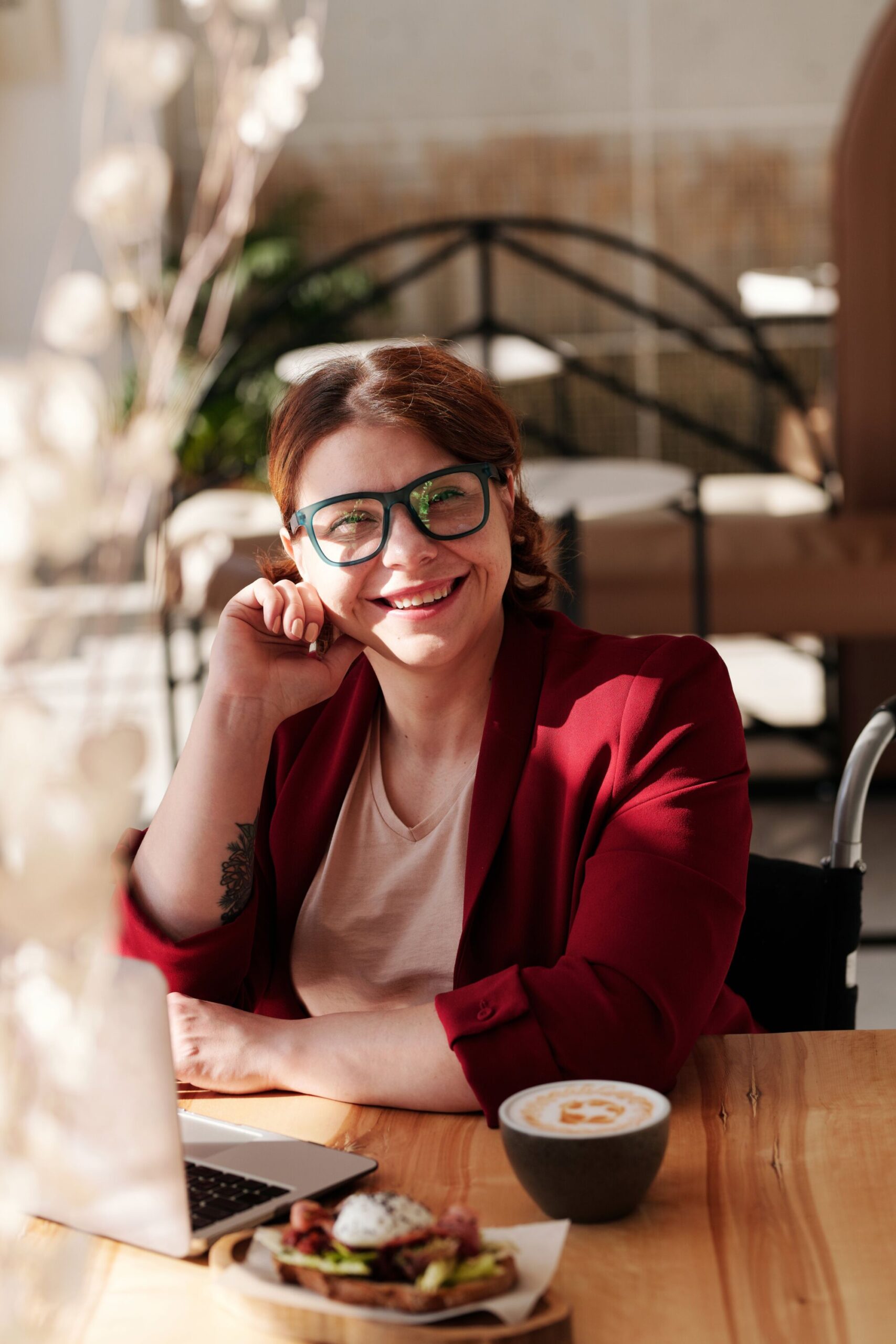 CEKOME AGENCE WEB08 SCALED | Cekome Femme en tenue décontractée professionnelle souriante et travaillant sur un ordinateur portable dans un espace de café.