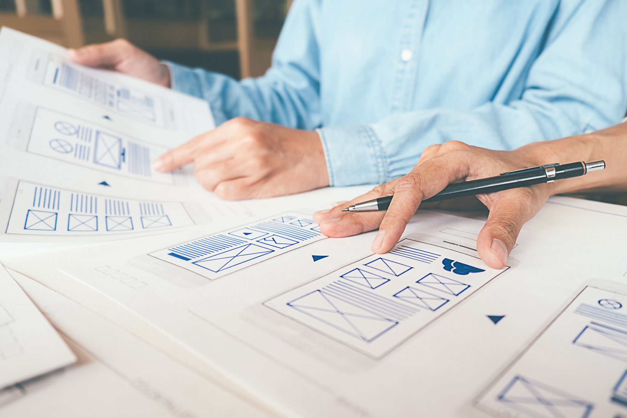 ADOBESTOCK_264548526 | Cekome Gros plan sur les mains d'une personne analysant des maquettes de conception d'interface utilisateur.