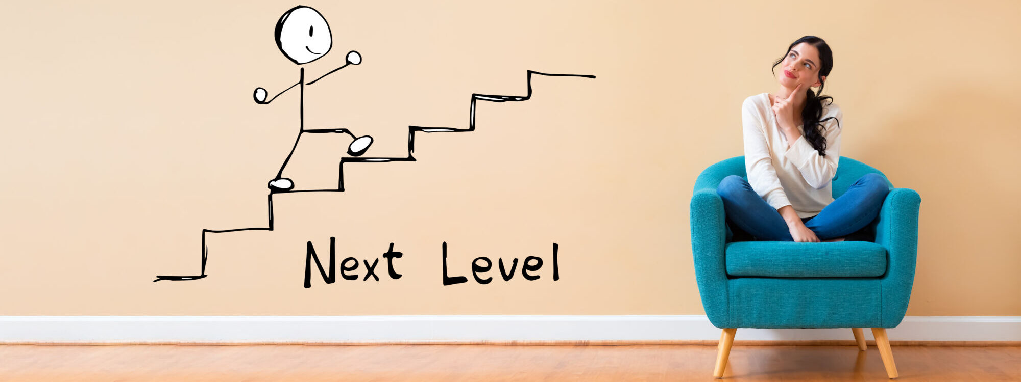 ADOBESTOCK_298640006 2000X750 | Cekome Femme assise sur un fauteuil bleu regardant un dessin mural représentant une personne grimpant des escaliers vers le texte "Next Level".