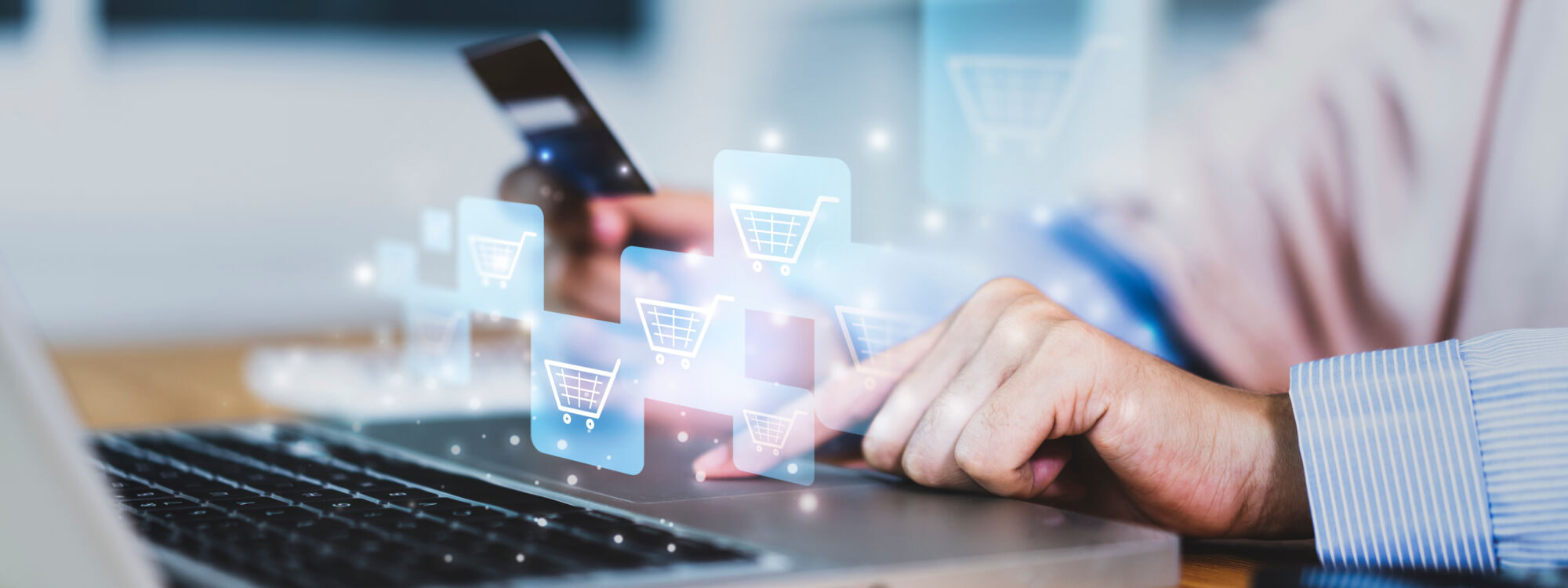 ADOBESTOCK_386084355 2000X750 | Cekome Main sélectionnant un panier d'achat virtuel sur un écran d'ordinateur portable avec une carte de crédit à la main.