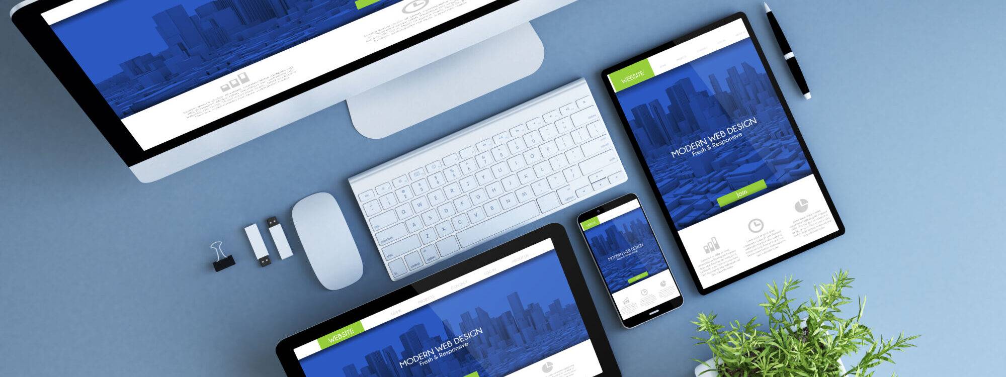 Gamme de dispositifs numériques présentant un site web de design moderne sur un bureau bleu-vert avec des accessoires de bureau.
