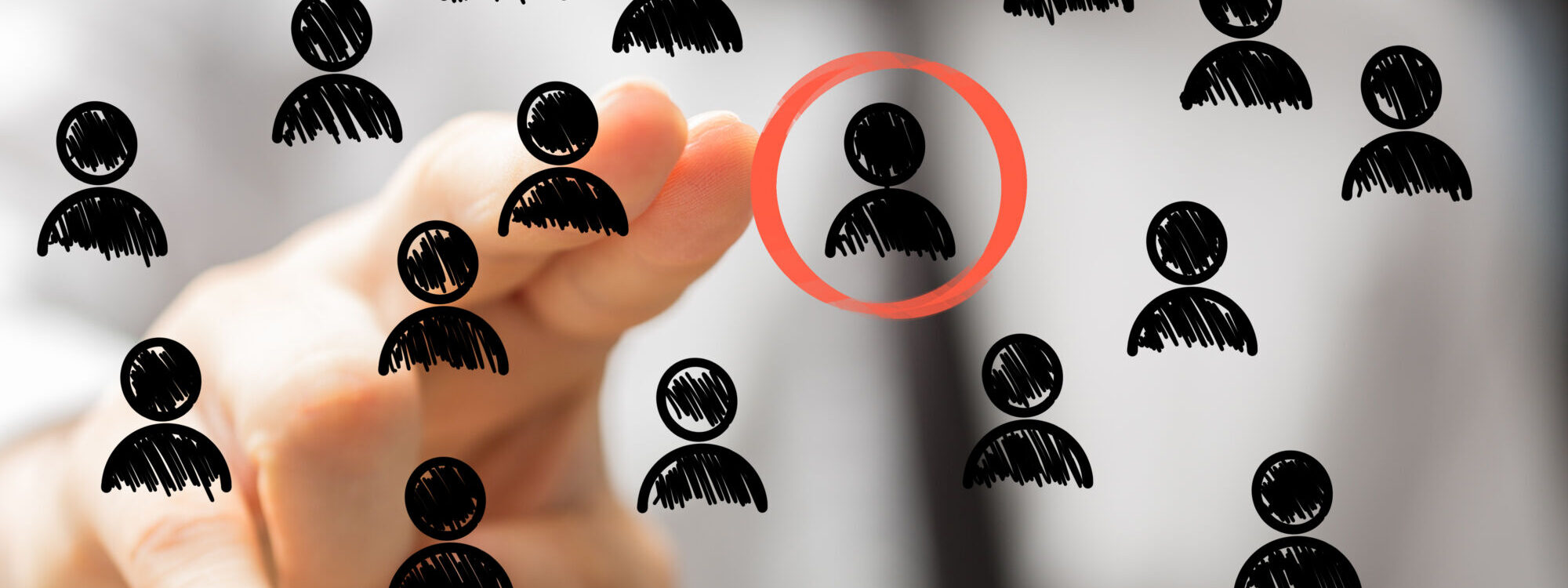 Main pointant vers un pictogramme cibl&eacute; parmi un groupe sur un fond conceptualisant le recrutement ou le choix