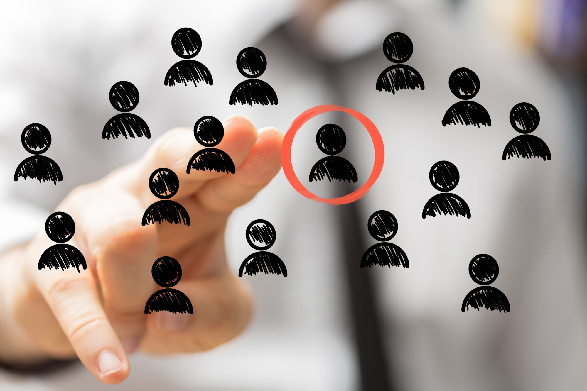 ADOBESTOCK_108881573 | Cekome Main pointant vers un pictogramme ciblé parmi un groupe sur un fond conceptualisant le recrutement ou le choix