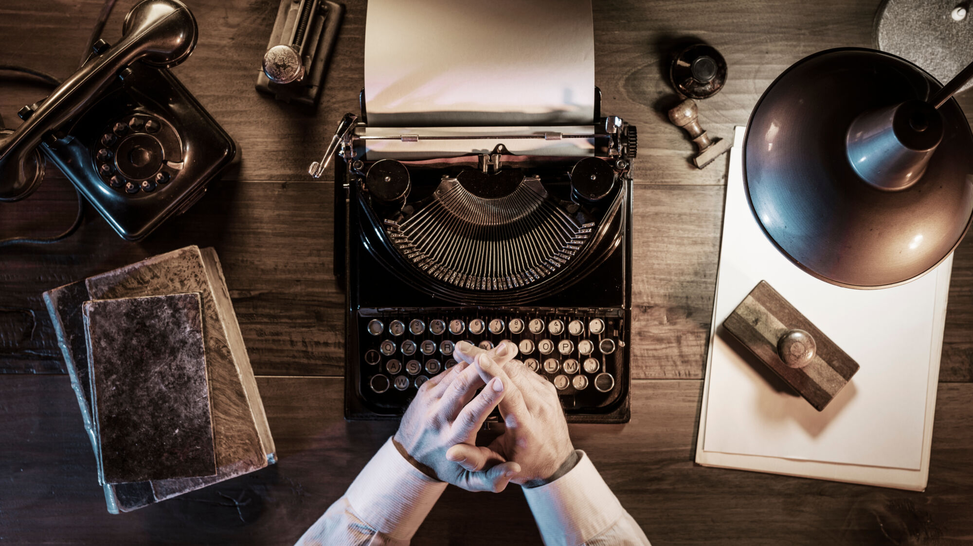 ADOBESTOCK_255548863 | Cekome Vue de dessus d'une personne utilisant une machine à écrire vintage sur un bureau en bois avec des objets anciens.