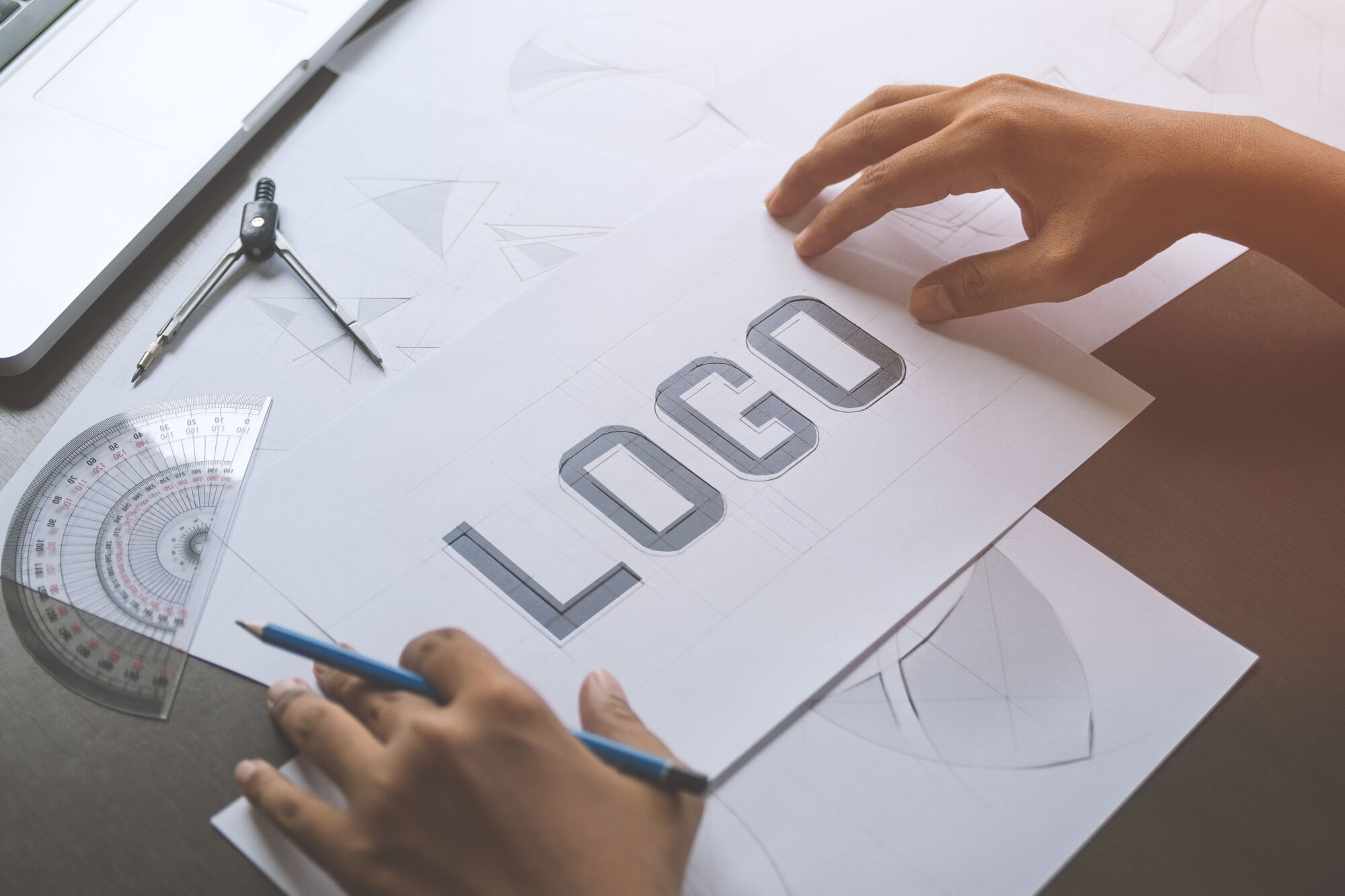 ADOBESTOCK_271407946 | Cekome Mains travaillant sur un dessin de concept de logo avec outils de dessin technique.
