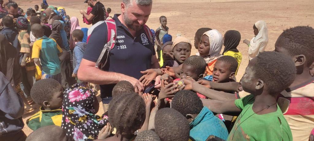 3 3 2 | Cekome Homme partageant un moment avec des enfants enthousiastes lors d'une distribution en plein air.