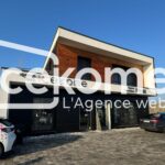 Fa&ccedil;ade moderne d'un b&acirc;timent de bureau avec enseigne de Cekome et v&eacute;hicules gar&eacute;s.