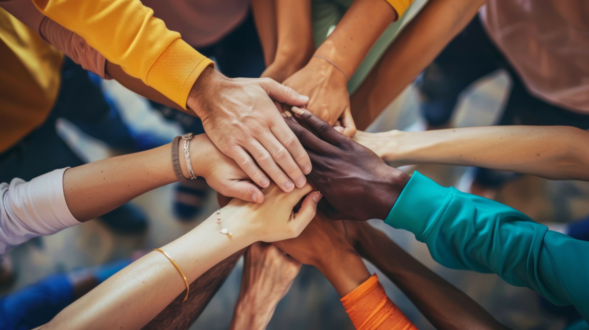 ADOBESTOCK_744749229 | Cekome Groupe de personnes de diverses ethnicités superposant leurs mains en signe d'unité.