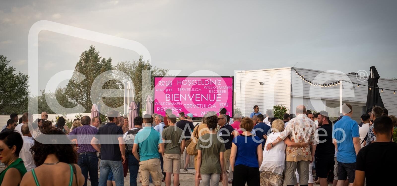 Participants devant un &eacute;cran affichant 'Bienvenue' en plusieurs langues &agrave; un &eacute;v&eacute;nement Cekome.