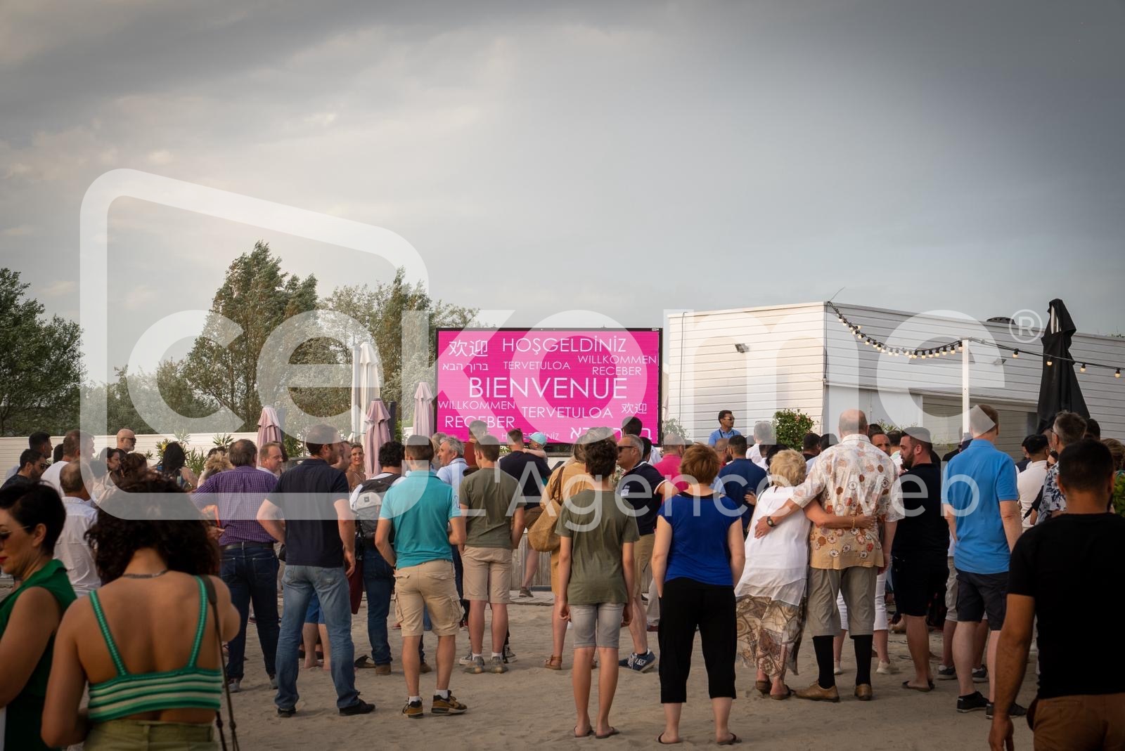 Participants devant un &eacute;cran affichant 'Bienvenue' en plusieurs langues &agrave; un &eacute;v&eacute;nement Cekome.