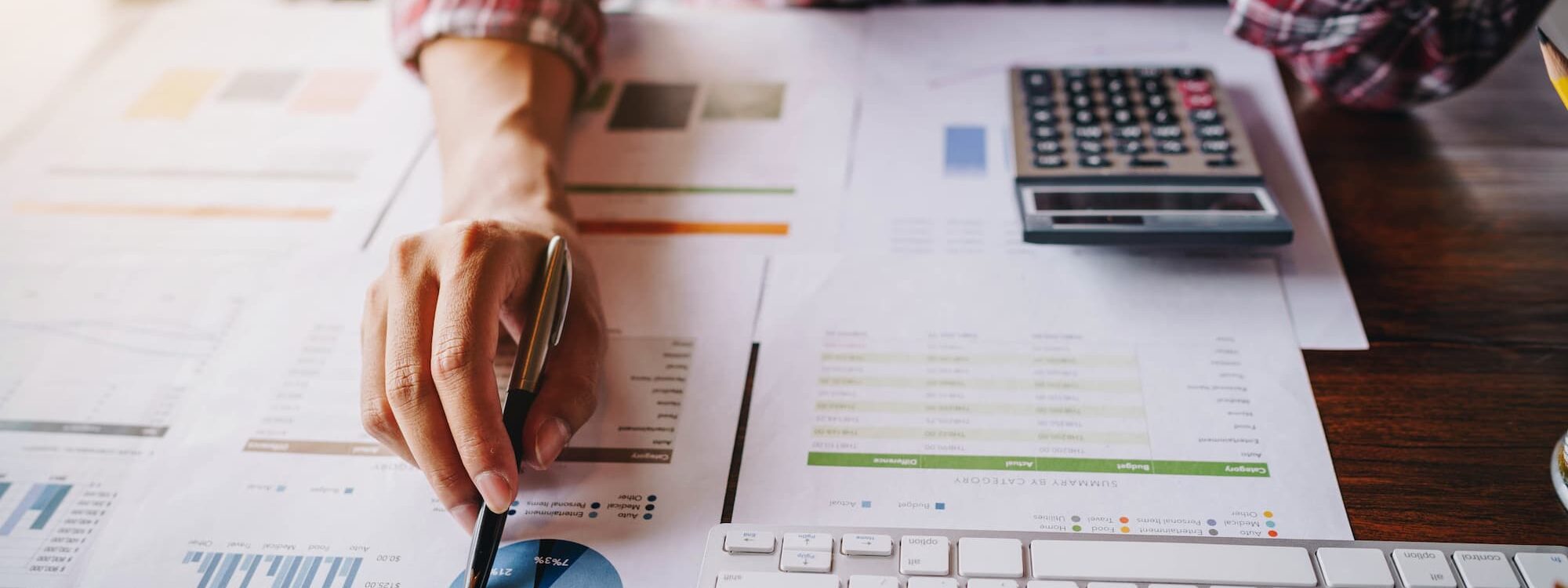 ADOBESTOCK_219391459 2000X750 | Cekome Professionnel travaillant sur des rapports financiers avec graphiques et calculatrice.