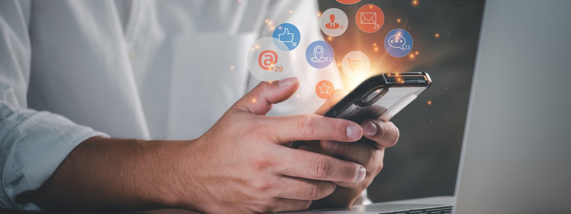 Personne utilisant un smartphone avec des ic&ocirc;nes de notifications de r&eacute;seaux sociaux flottantes.