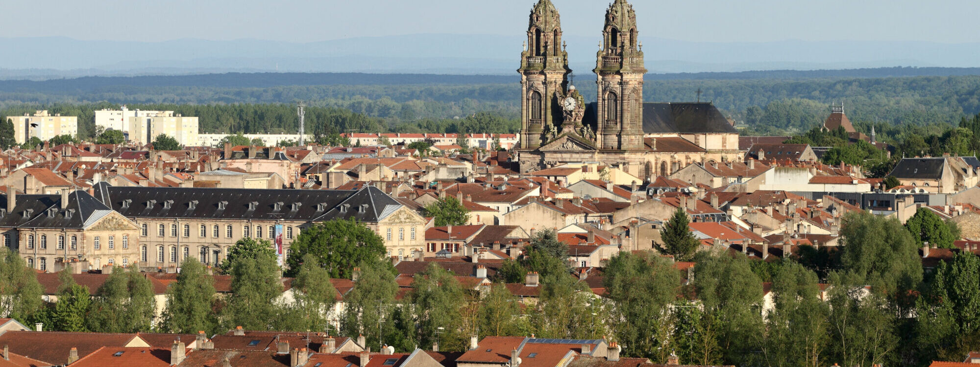 Vue panoramique sur une ville avec une cath&eacute;drale &agrave; deux clochers dominant les toits.