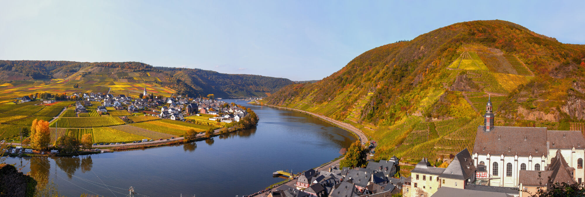 Vue a&eacute;rienne d'un village bordant une rivi&egrave;re avec des vignobles sur les coteaux.