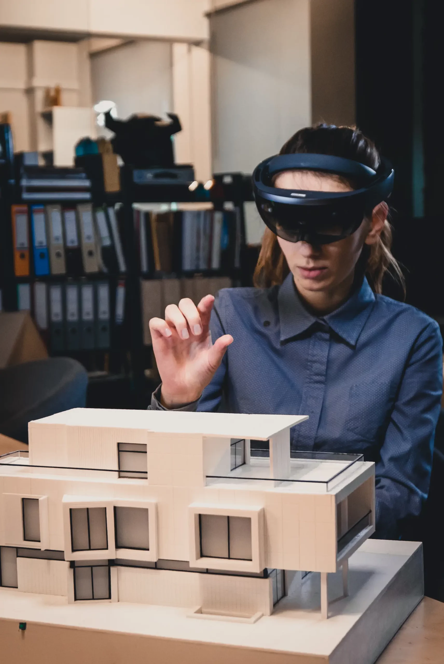 Architecte utilisant un casque de réalité augmentée pour visualiser une maquette de bâtiment moderne.