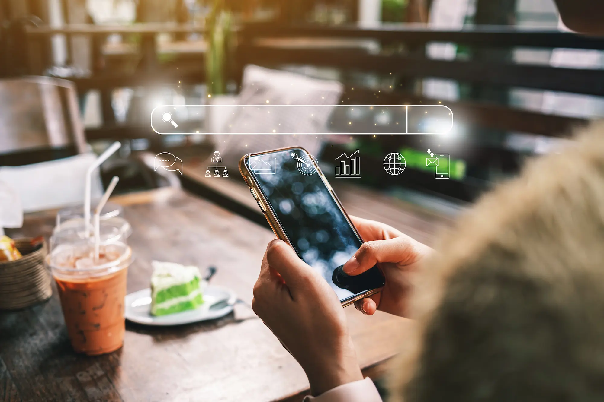 Personne utilisant un smartphone dans un café avec des icônes de recherche et de marketing numérique en surimpression