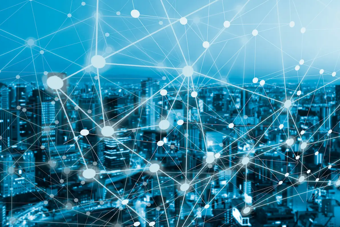 ADOBESTOCK_332010931 | Cekome Vue d'une ville avec un réseau de connexions numériques représenté par des points et des lignes lumineuses.