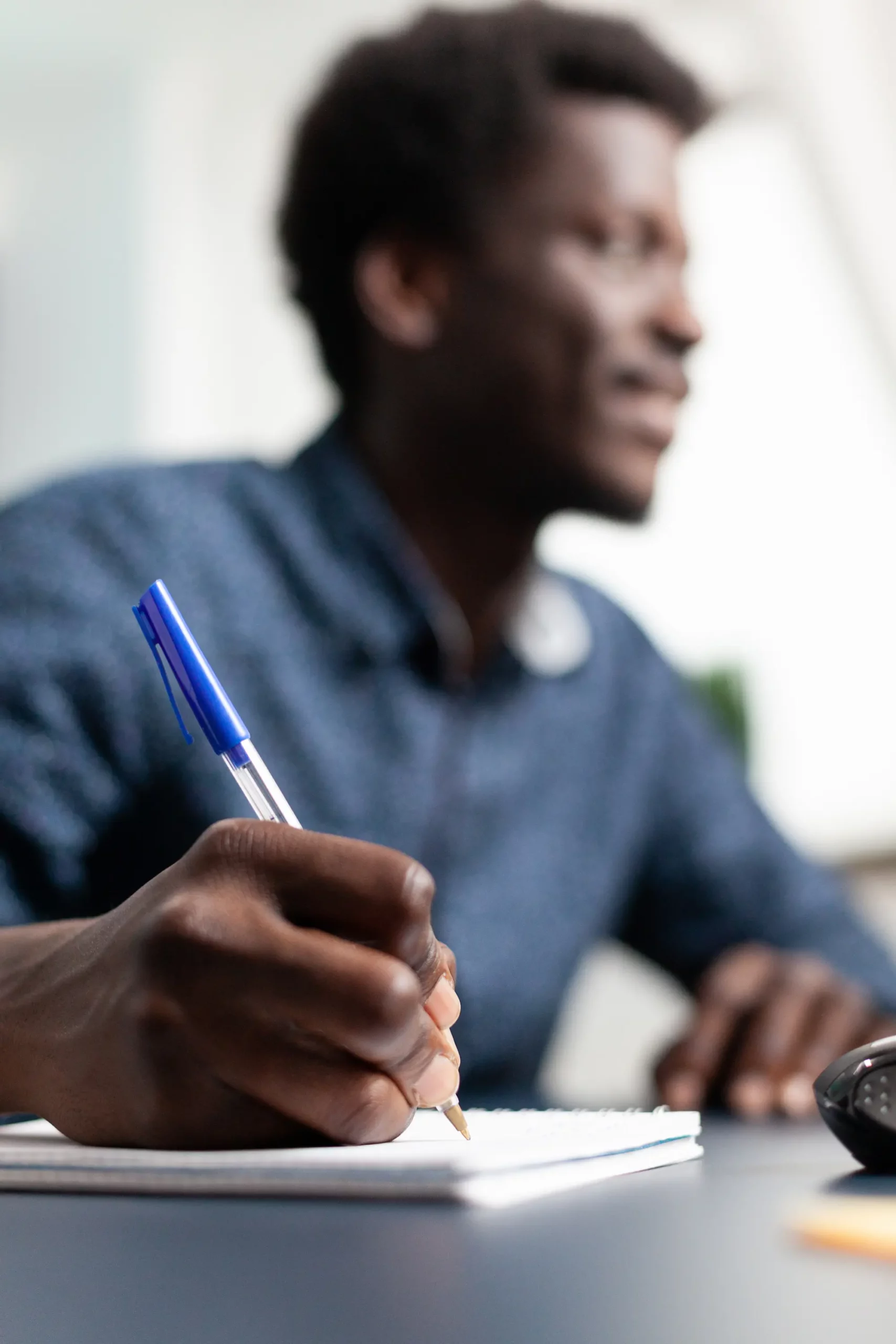 ADOBESTOCK_445320692 SCALED | Cekome Homme écrivant dans un carnet avec un stylo bleu