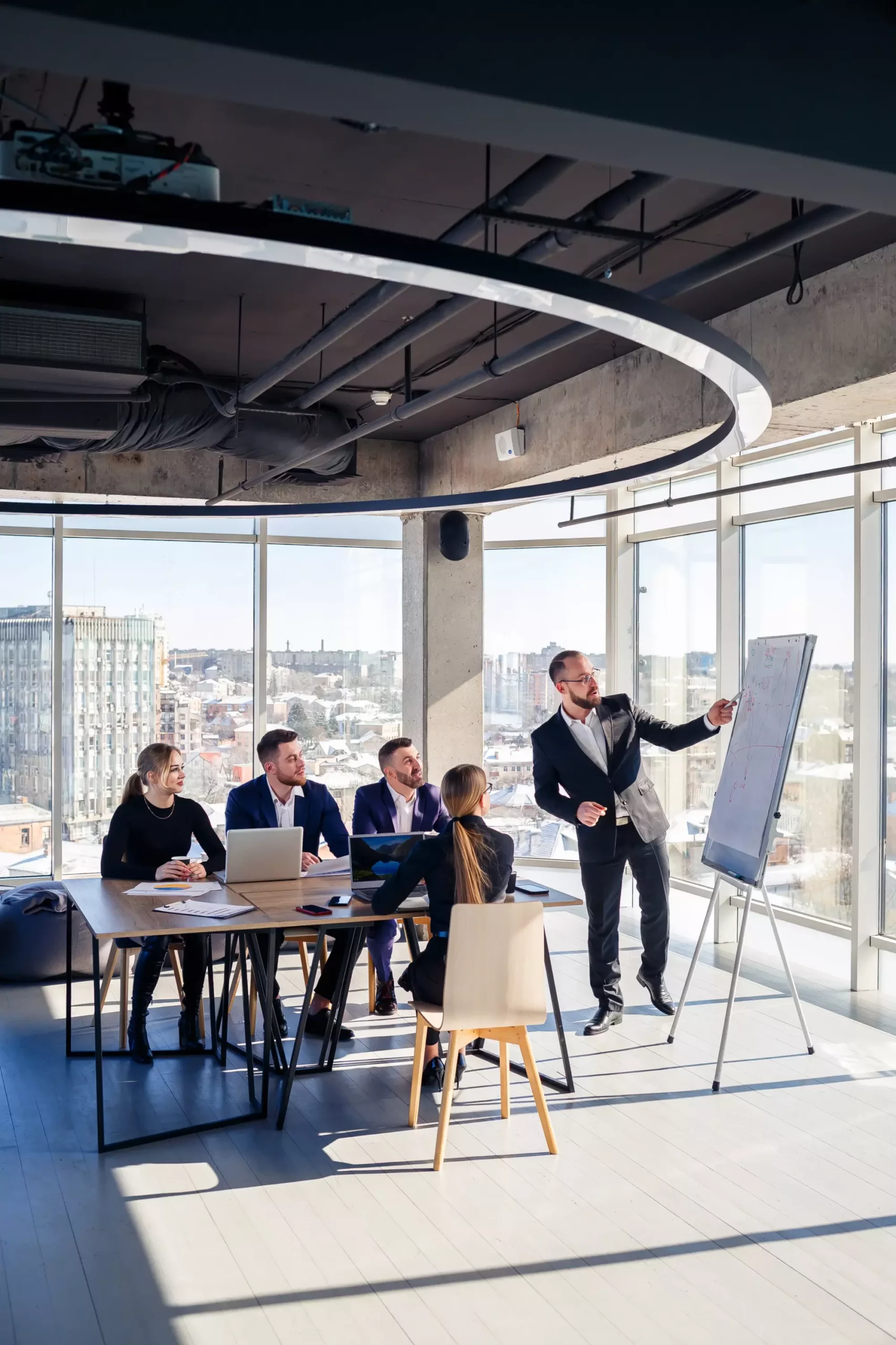 Réunion d'affaires dans une salle moderne avec un homme en costume faisant une présentation sur un tableau blanc