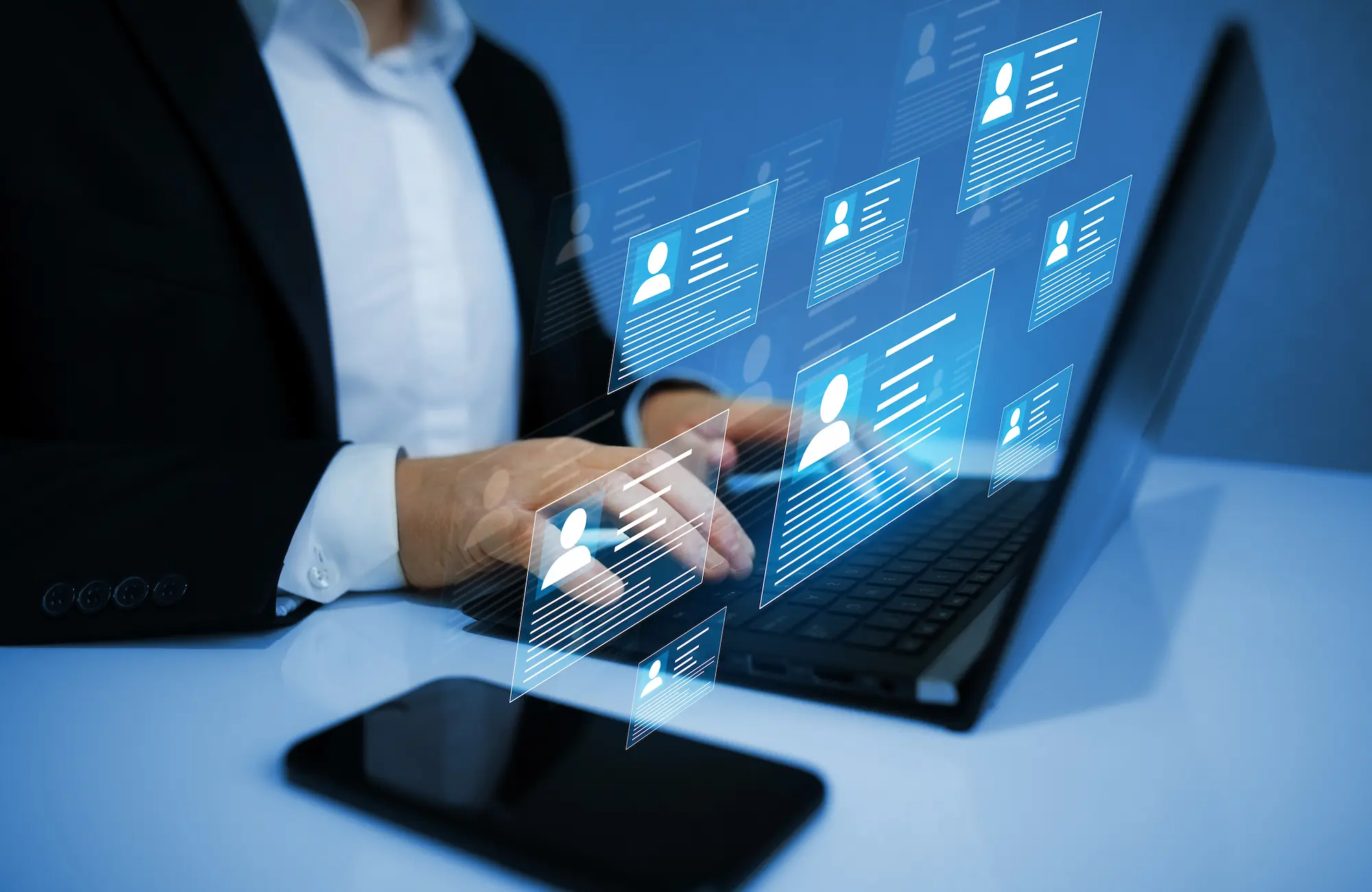 Personne en costume utilisant un ordinateur portable avec des icônes virtuelles de profils utilisateur flottants