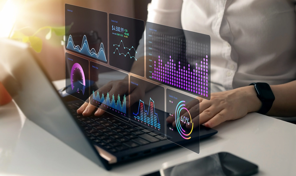 ADOBESTOCK_734190069 | Cekome Personne travaillant sur un ordinateur portable avec des graphiques de données numériques en hologramme.