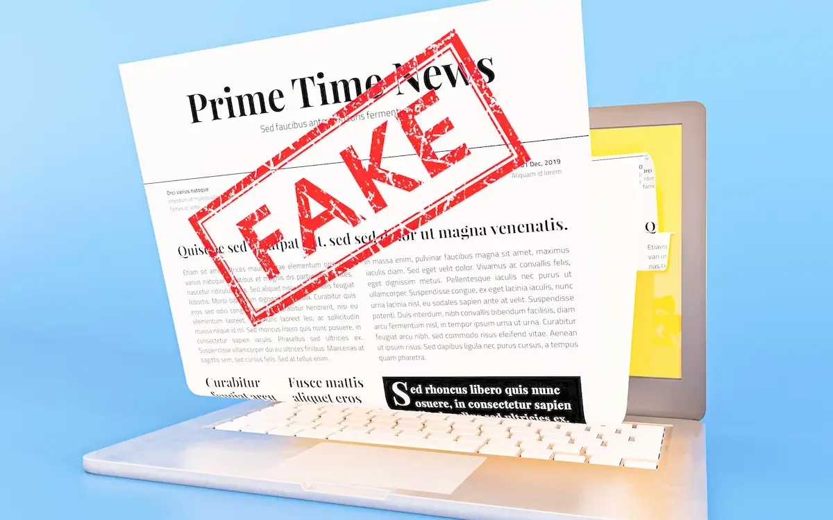 Ordinateur affichant une fausse actualit&eacute; avec un tampon rouge "FAKE" sur l'&eacute;cran