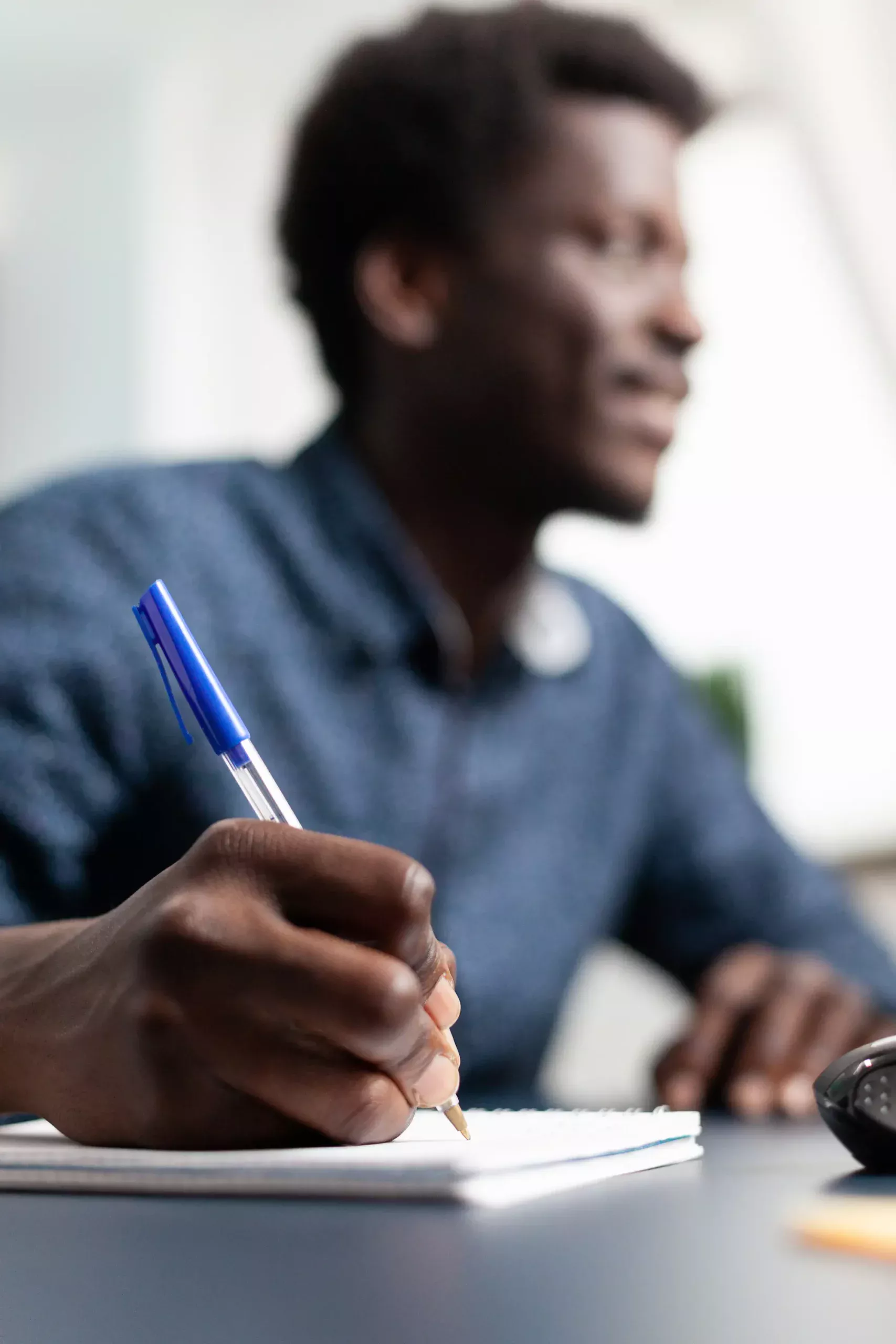 ADOBESTOCK_445320692 SCALED | Cekome Homme écrivant dans un carnet avec un stylo bleu