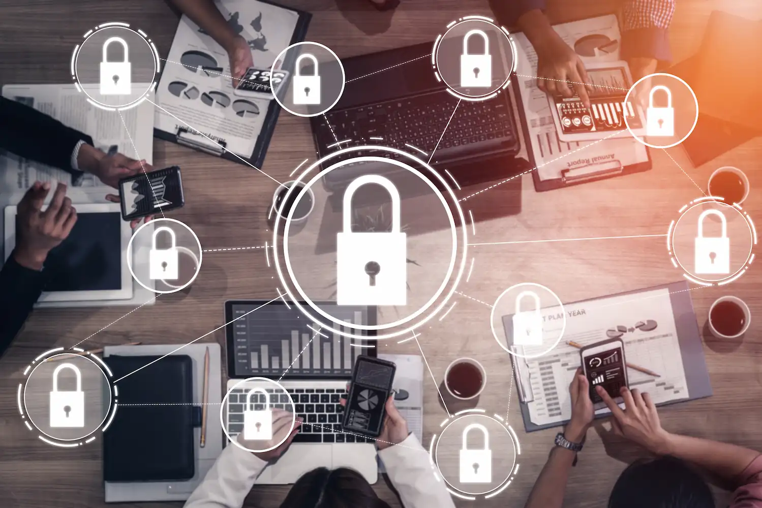ADOBESTOCK_274360957 | Cekome Réunion d'affaires sur la cybersécurité avec des professionnels utilisant des ordinateurs portables et des smartphones, entourés d'icônes de cadenas symbolisant la protection des données.