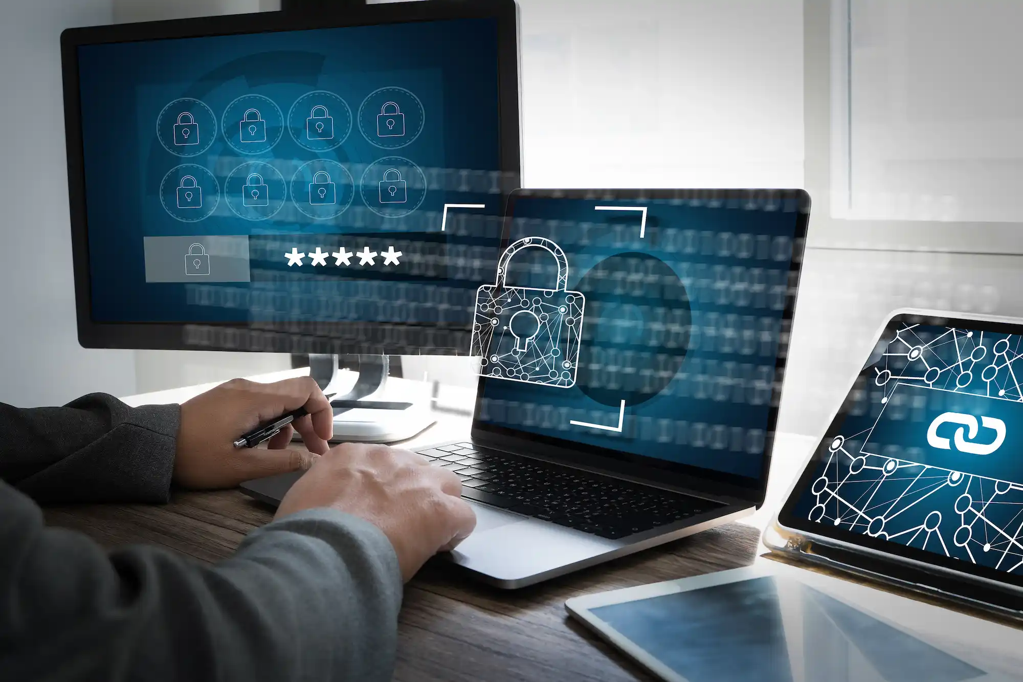 ADOBESTOCK_319072548 | Cekome Personne travaillant sur un ordinateur avec des écrans affichant des icônes de sécurité et un cadenas, illustrant la cybersécurité et la protection des données.