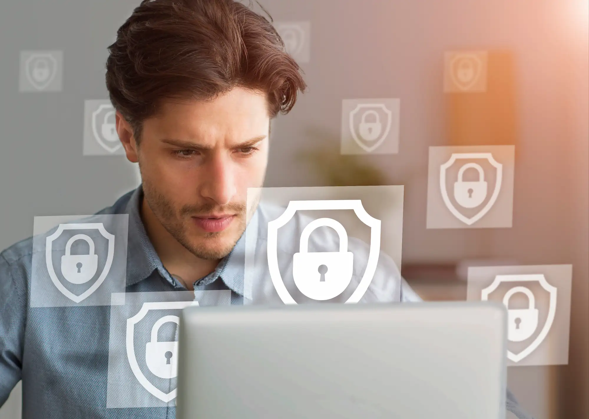 ADOBESTOCK_390121096 | Cekome Homme concentré travaillant sur un ordinateur avec des icônes de sécurité et de cybersécurité en surimpression.