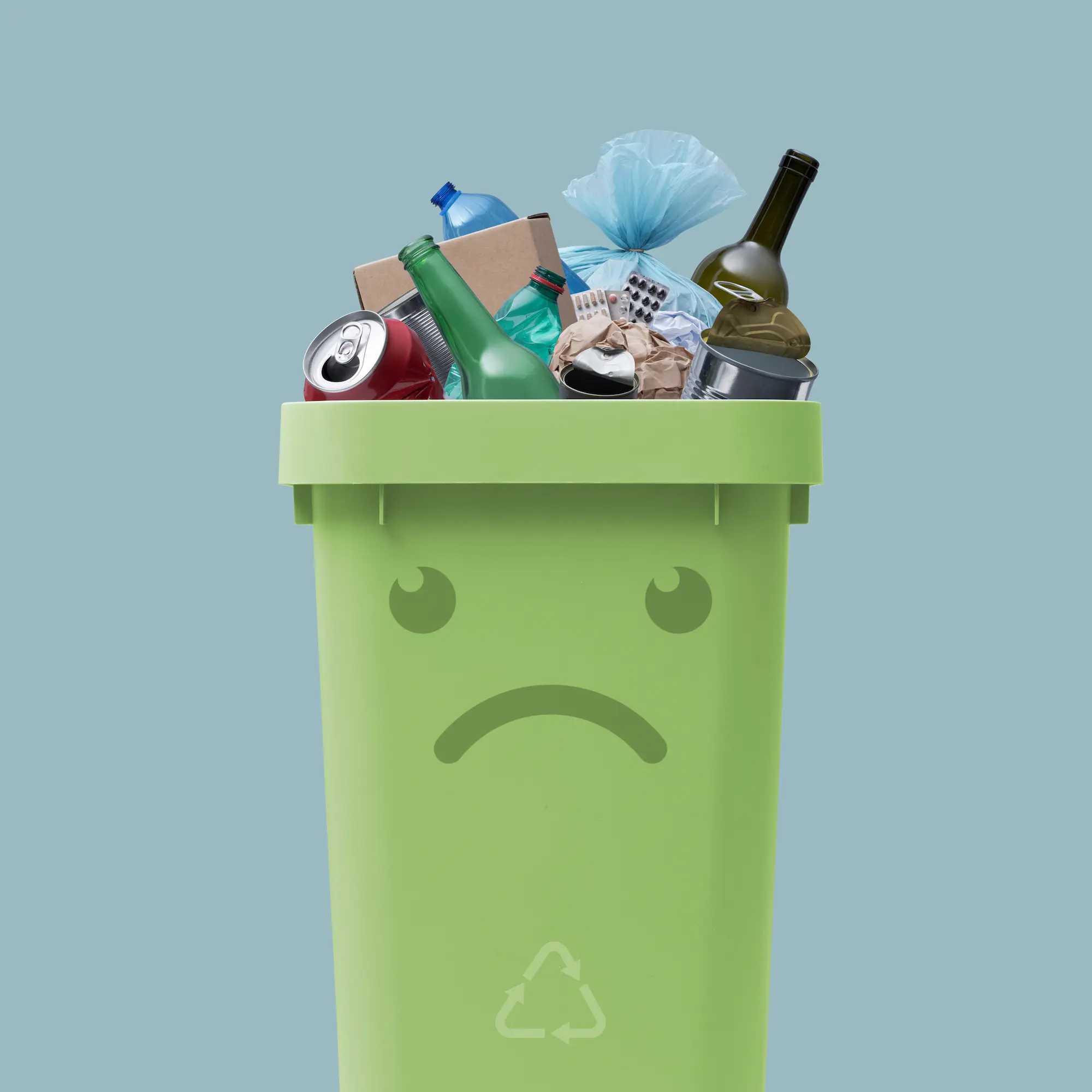 ADOBESTOCK_495098862 | Cekome Poubelle de recyclage verte avec un visage triste, débordant de déchets variés, symbolisant le problème de la gestion des déchets et du tri sélectif.