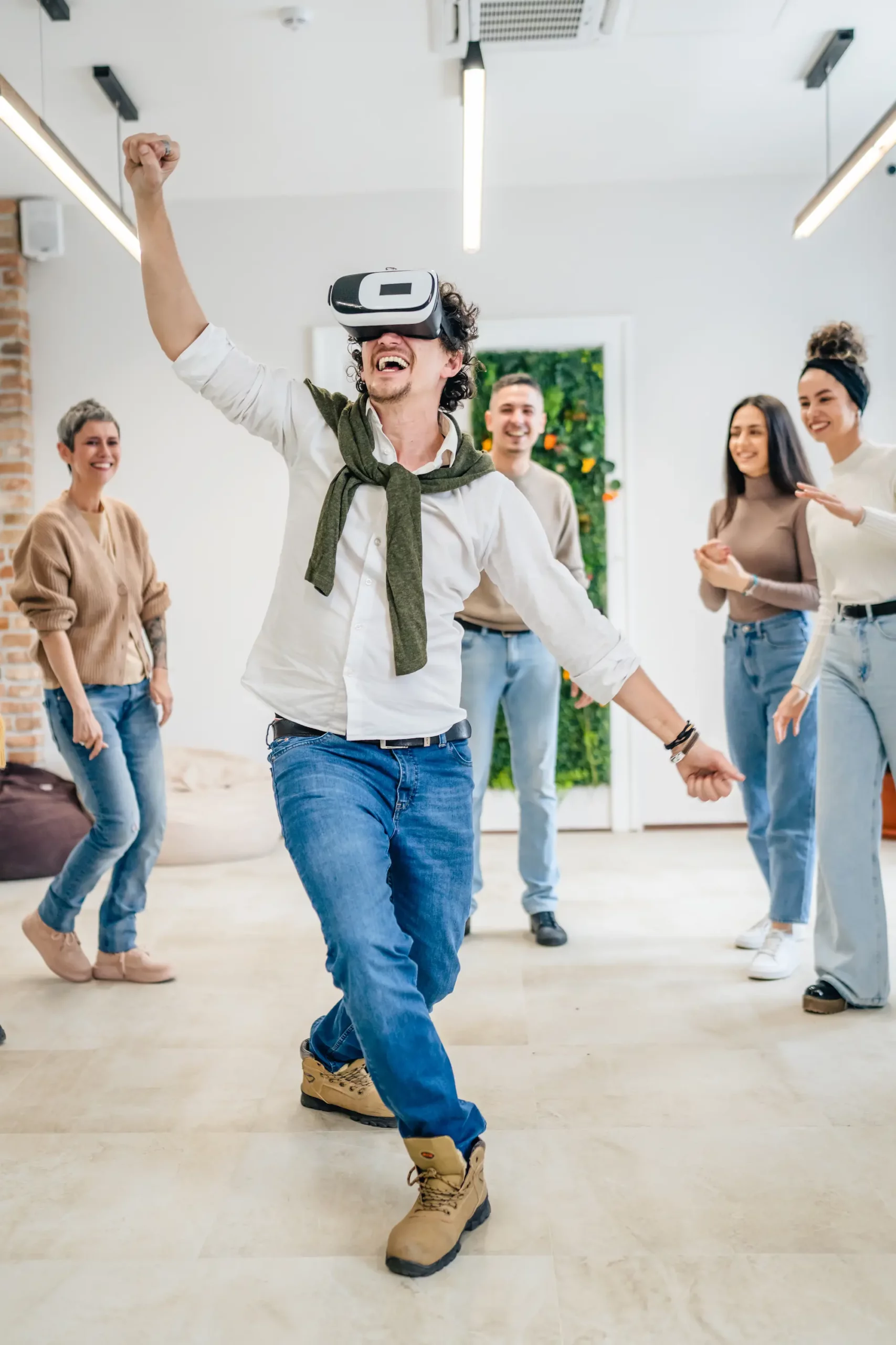 ADOBESTOCK_587117850 SCALED | Cekome Homme portant un casque de réalité virtuelle dansant joyeusement devant un groupe de personnes souriantes