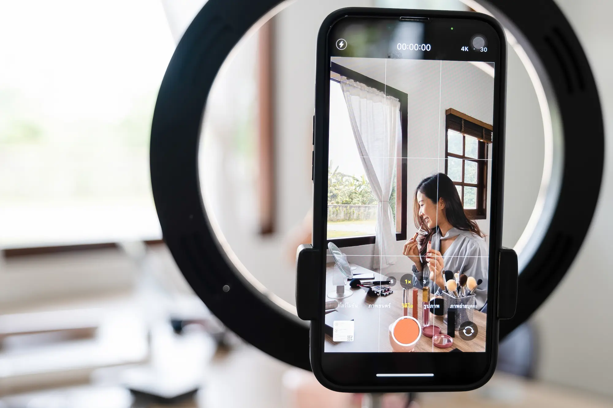Influenceuse se maquillant devant une caméra de smartphone avec éclairage annulaire