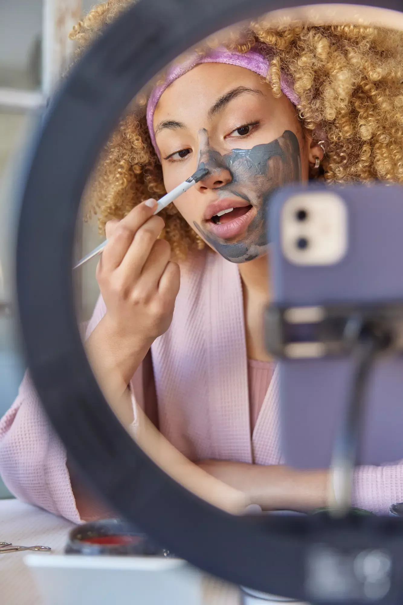 ADOBESTOCK_563672217 | Cekome Femme faisant la promotion d'un masque facial tout en l'appliquant devant un smartphone