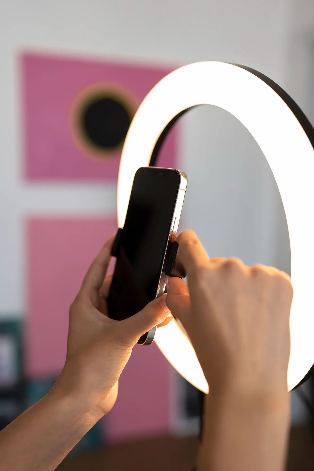 2149602026 | Cekome Gros plan sur des mains fixant un smartphone sur un trépied avec anneau lumineux, prêt pour un enregistrement vidéo.