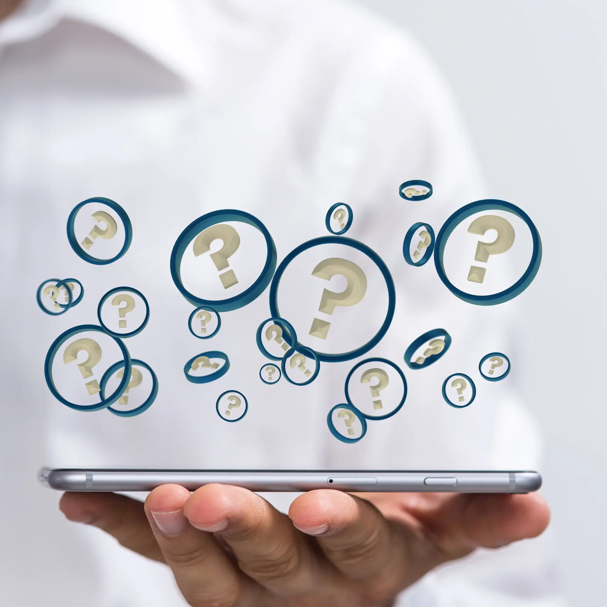 Main tenant un smartphone avec des bulles contenant des points d'interrogation flottants