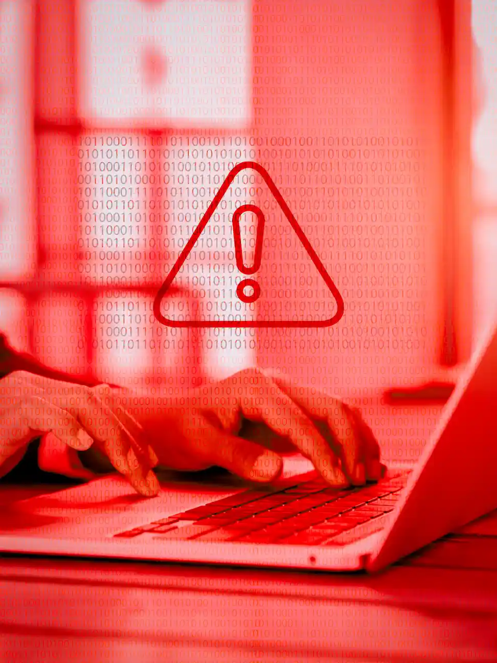 ADOBESTOCK_567928822 | Cekome Alerte cybersécurité avec un avertissement sur fond rouge et une personne utilisant un ordinateur portable.