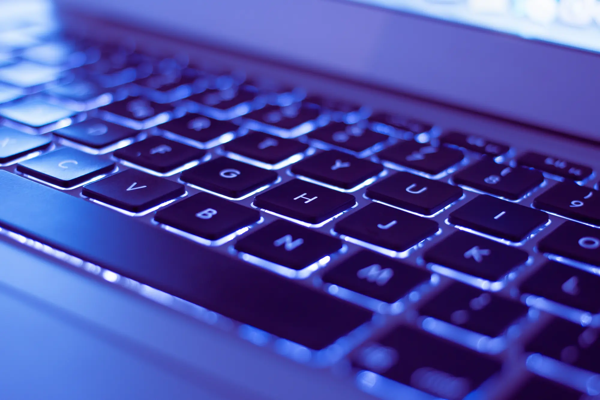 ADOBESTOCK_92015008 | Cekome Clavier rétroéclairé d'un ordinateur portable en gros plan avec éclairage bleu.