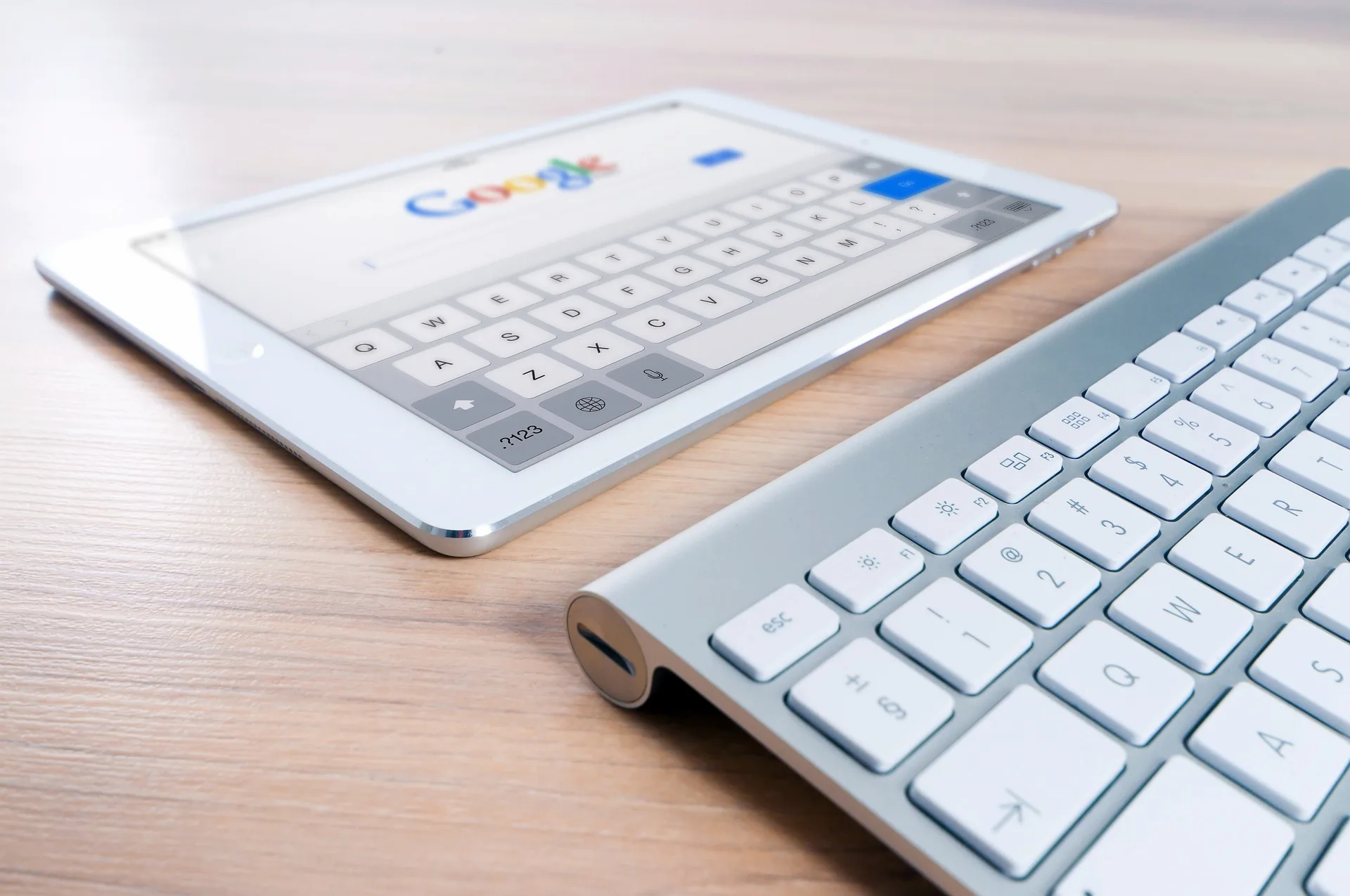 Tablette affichant Google à côté d'un clavier sans fil sur une table en bois
