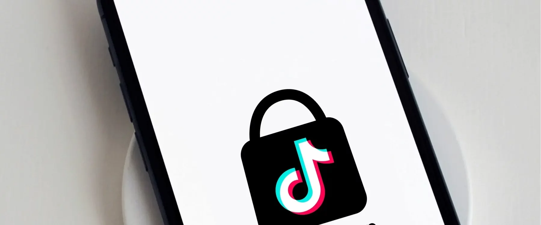 Smartphone affichant le logo TikTok Shop sur écran blanc, posé sur un chargeur sans fil.