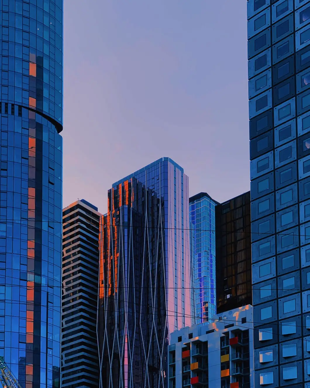 INFRASTRUCTURE | Cekome Gratte-ciels modernes en verre reflétant les couleurs du coucher de soleil dans une ville urbaine.