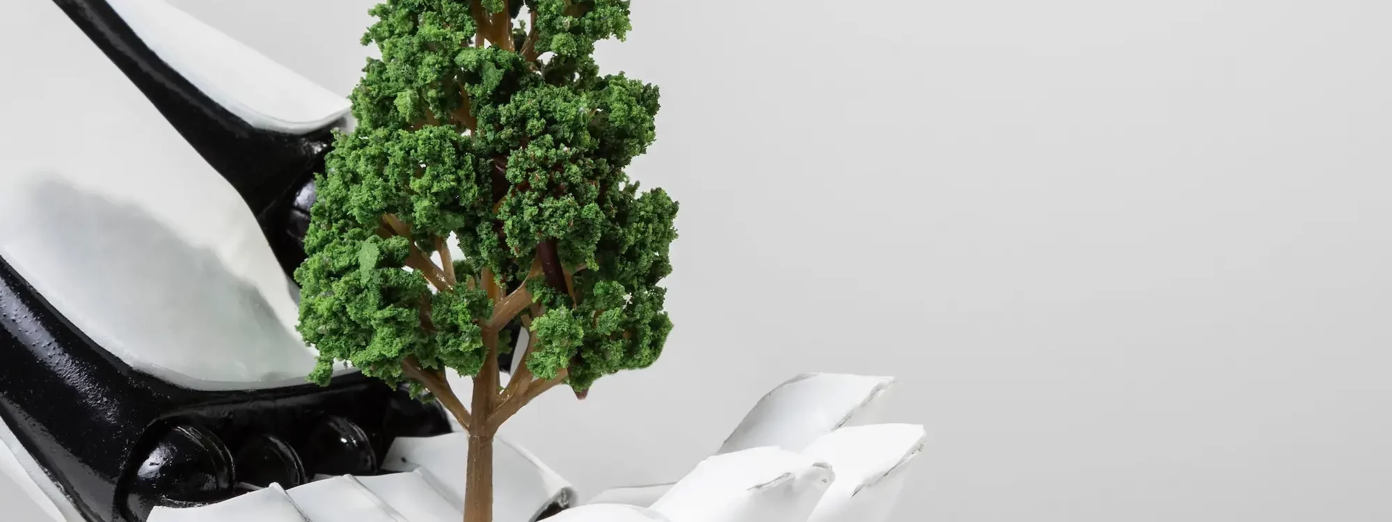 Main robotique tenant un petit arbre, illustrant l'alliance entre intelligence artificielle et écologie pour un futur durable.