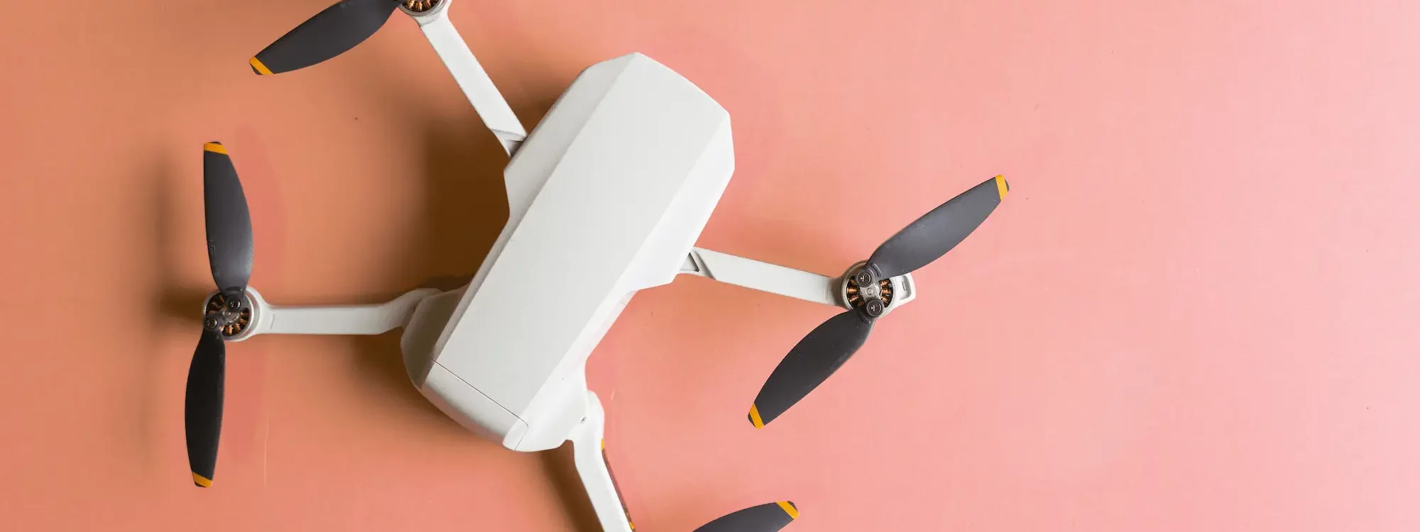 Drone blanc vu de dessus sur fond rose, illustrant la transition vers des syst&egrave;mes autonomes pilot&eacute;s par intelligence artificielle