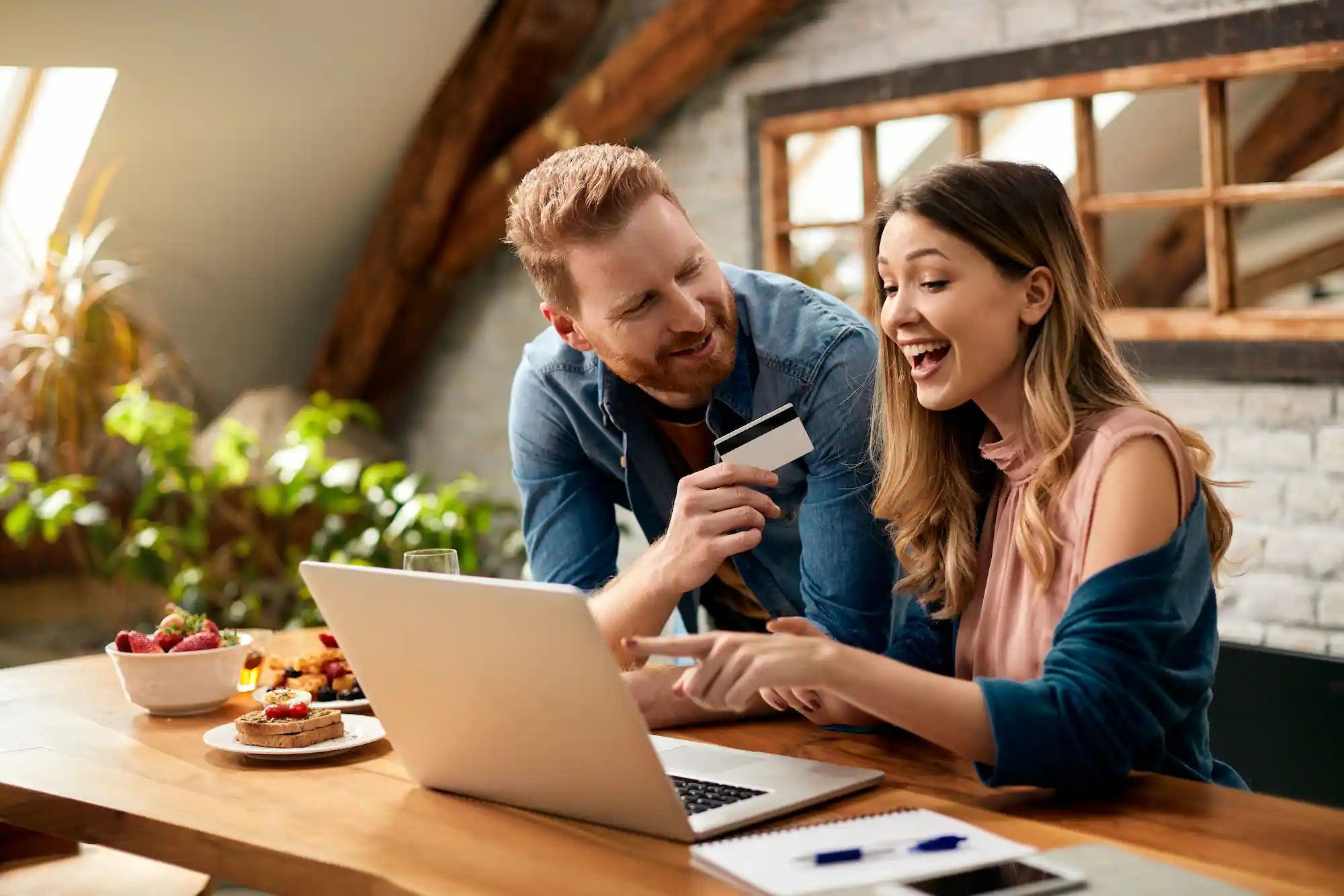 HAPPY COUPLE HAVING FUN WHILE ONLINE SHOPPING HOME | Cekome Couple souriant faisant des achats en ligne à domicile avec un ordinateur portable et une carte bancaire