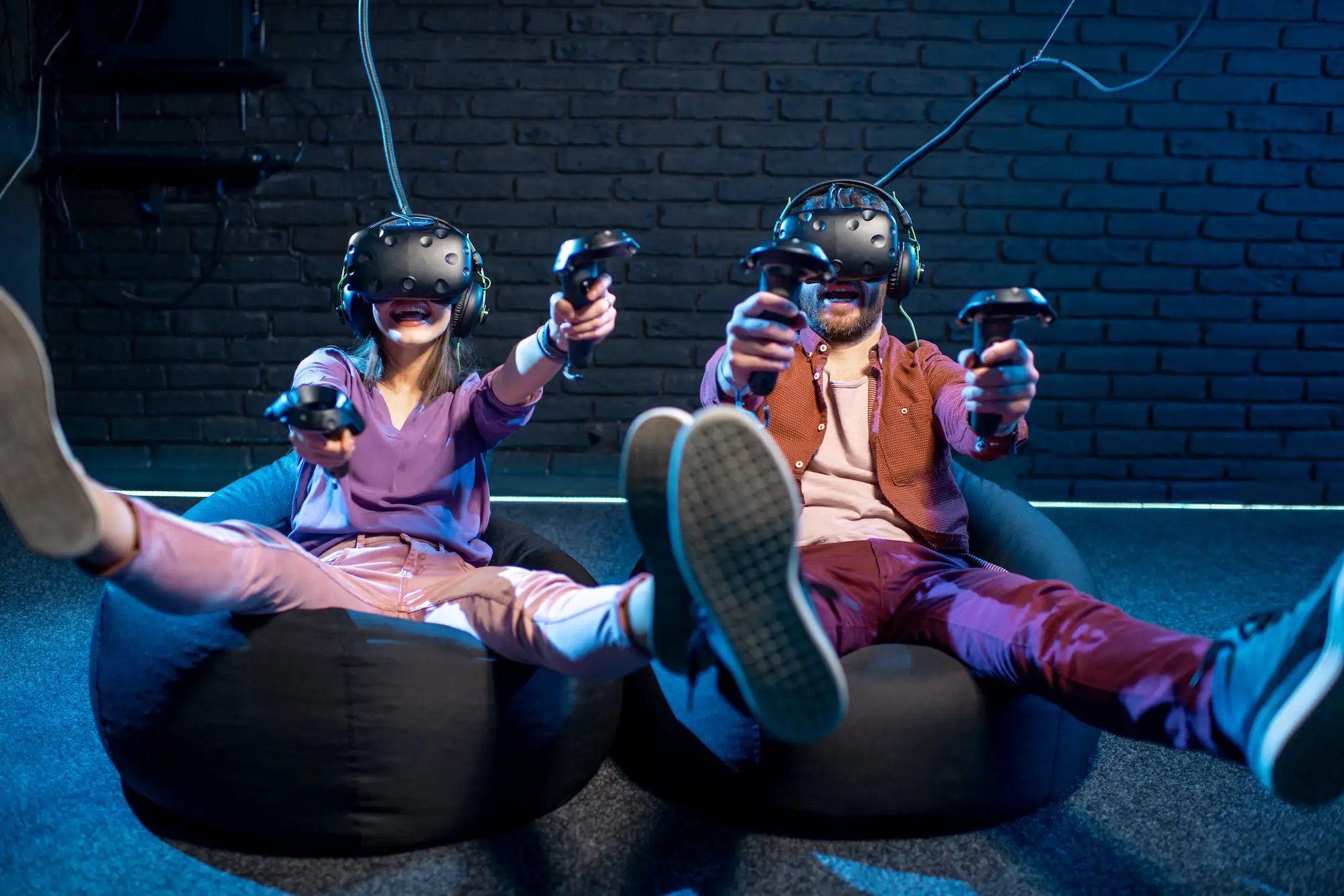 Deux personnes assises avec des casques VR et manettes, en pleine expérience de jeu en réalité virtuelle.