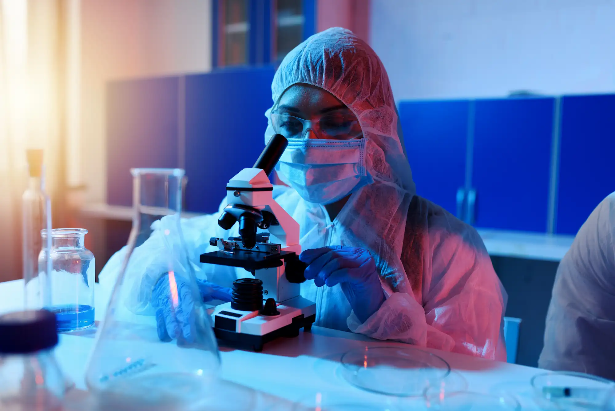 ADOBESTOCK_419102781 | Cekome Chercheuse en tenue de protection utilisant un microscope dans un laboratoire scientifique