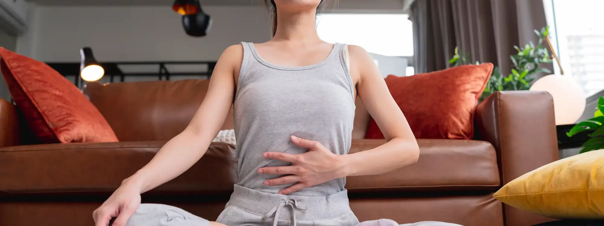 Femme en tenue d&eacute;contract&eacute;e pratiquant la m&eacute;ditation avec un casque de r&eacute;alit&eacute; virtuelle dans un salon cosy
