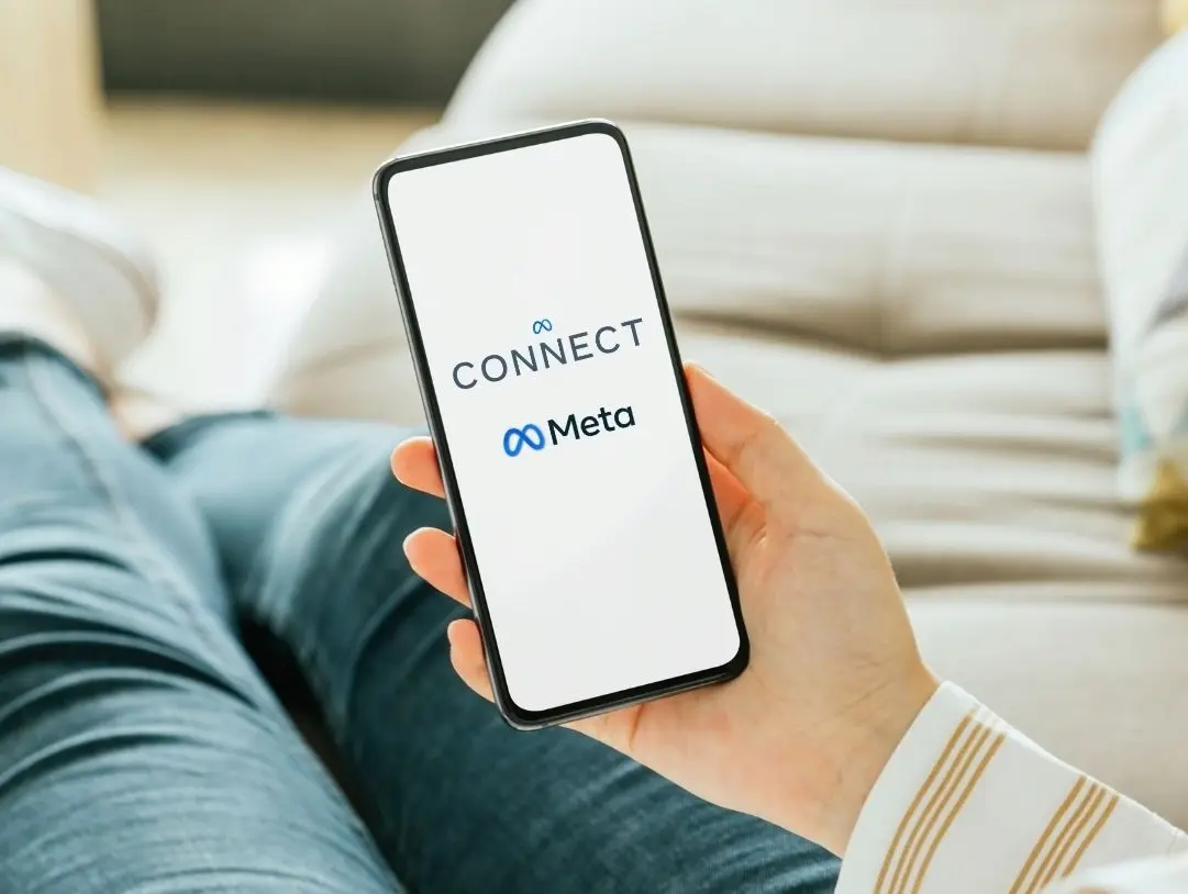 Main tenant un smartphone affichant l’écran de connexion Meta Connect, illustrant l’interaction humaine avec les technologies connectées