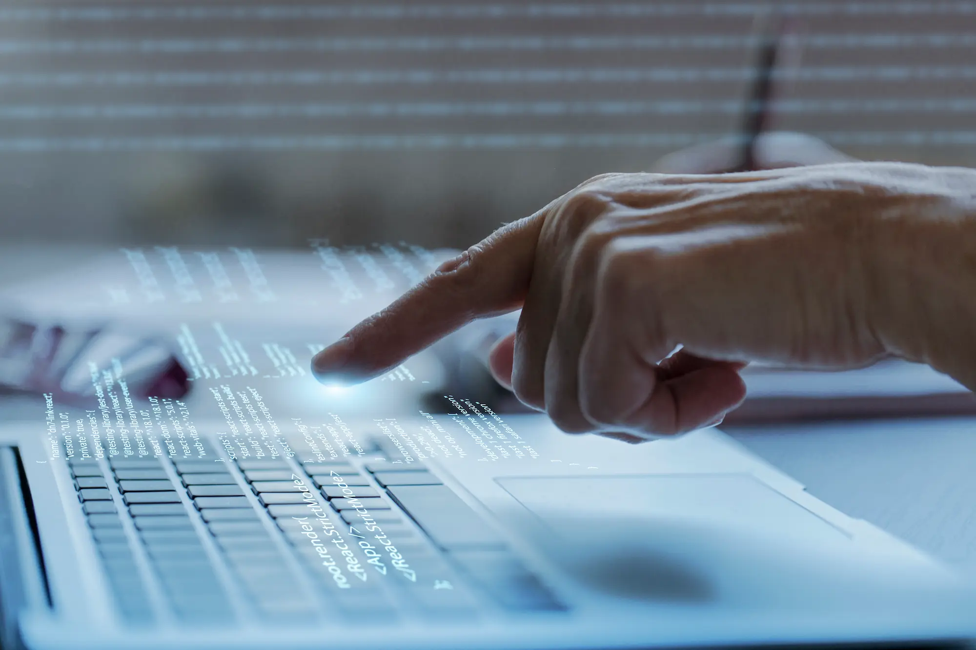 Main pointant du doigt un écran virtuel de code au-dessus d’un clavier d’ordinateur portable, représentant le développement d’agents autonomes et d’intelligences artificielles