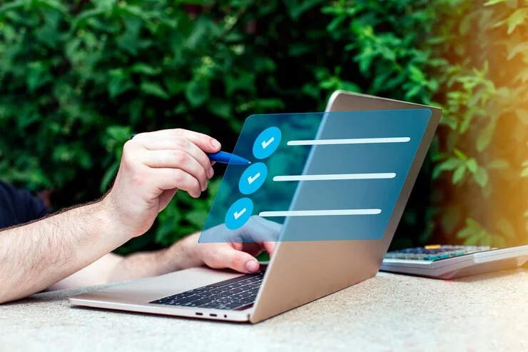 Main cochant une liste virtuelle sur un écran d’ordinateur portable en plein air